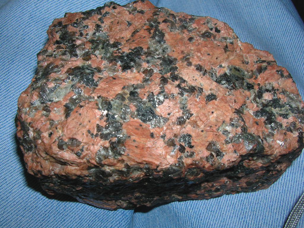 Handstück Alkali-Feldspat-Granit: rosa Kalifeldspat, glasiger Quarz, schwarzer Biotit